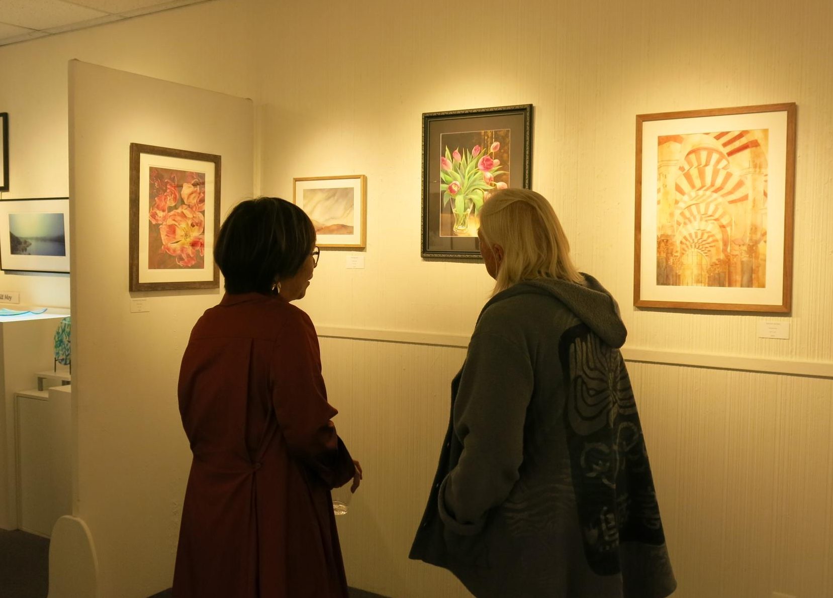 Artist Mami Weber discusses her artwork with a viewer at Gallery 9 in Los Altos during her exhibition’s opening celebration on Friday. Weber said she paints in watercolor because of the medium's capacity for organic movement. "I allow the paint to move freely, accepting what cannot be fully controlled," Weber said. "I invite viewers to slow down, sense what remains, and reflect on moments that once felt ordinary, yet continue to resonate."